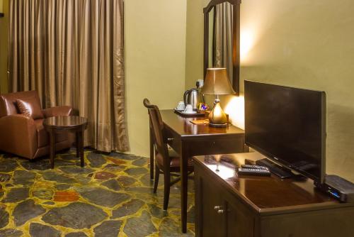 a hotel room with a desk with a computer and a chair at Big Valley Game Lodge in Lobatse