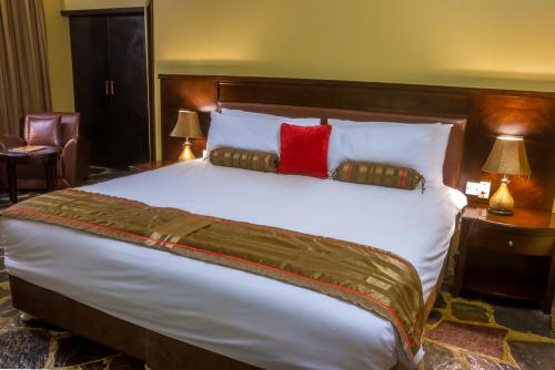 a bedroom with a large white bed with two red pillows at Big Valley Game Lodge in Lobatse