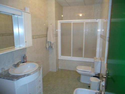 a bathroom with a sink and a toilet and a window at Hostal Los Claveles in Baena