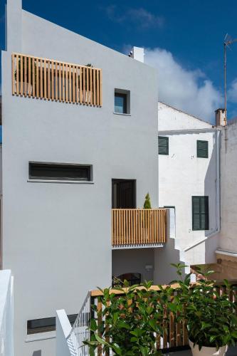 a white building with a wooden balcony on it at Sodium Boutique Hotel in Ciutadella