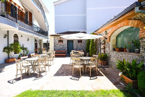 an outdoor patio with tables and chairs and an umbrella at Rose Garden Hotel in Shkodër