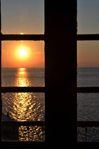 a view of the ocean through a window at sunset at Petridi House in Symi