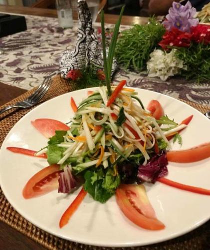 a white plate with a salad on a table at Villa Taman Kanti in Ubud