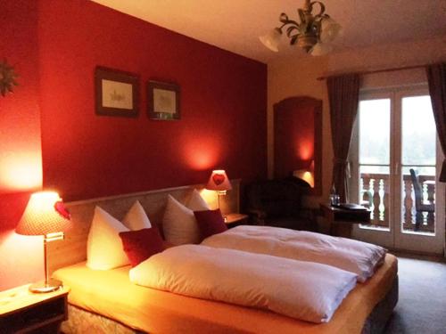 a bedroom with a large bed with a red wall at Bäckeralm© - B&B 16 + in Mittenwald