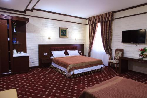 um quarto de hotel com uma cama e uma televisão de ecrã plano em Rakat Plaza em Tashkent