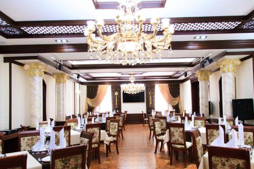 a dining room with tables and chairs and a chandelier at Rakat Plaza in Tashkent