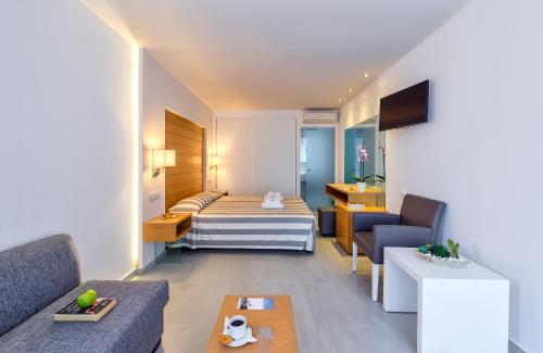 ein Hotelzimmer mit einem Bett und einem Sofa in der Unterkunft Happy Days Beach Hotel in Georgioupoli