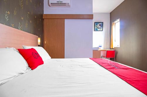 1 dormitorio con 1 cama blanca grande con almohadas rojas en RedDoorz Syariah near BTC Fashion Mall, en Bandung