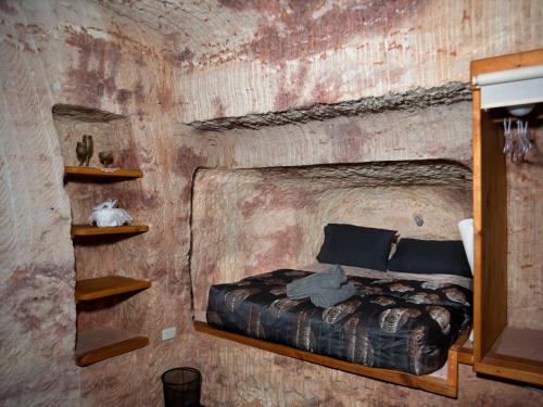 1 dormitorio con 1 cama en una habitación con una pared de ladrillo en Ali's Underground Studio, en Coober Pedy