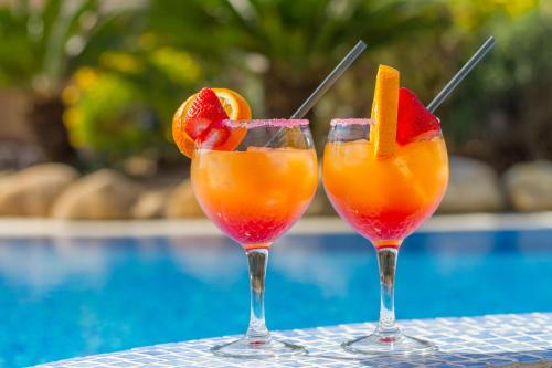 two cocktails with fruit on a table next to a pool at Golden Port Salou & Spa in Salou