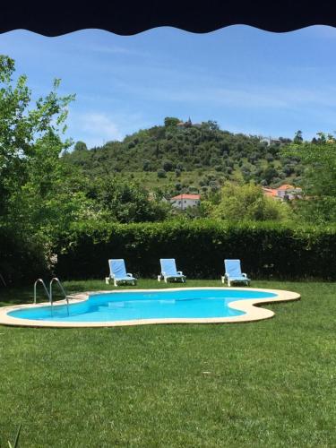 a swimming pool with two lounge chairs in the grass at Horta dos Cedros in Tomar