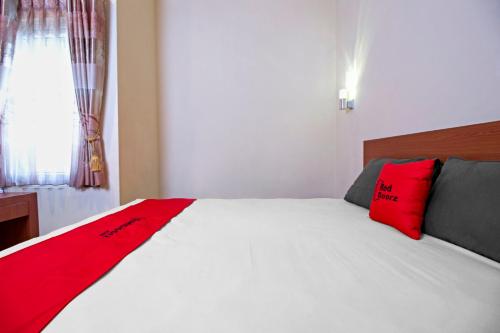 a bedroom with a white bed with red pillows at RedDoorz near Trans Studio Mall 2 in Bandung