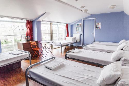 a room with three beds and a table and chairs at St Christopher's Inn Paris - Canal in Paris