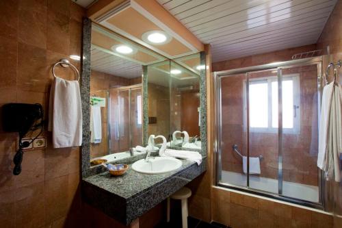 La salle de bains est pourvue d'un lavabo et d'un grand miroir. dans l'établissement Hotel Cabana, à Benidorm