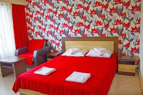 a hotel room with a red bed and a chair at Complex Chayka Guest House in Byala