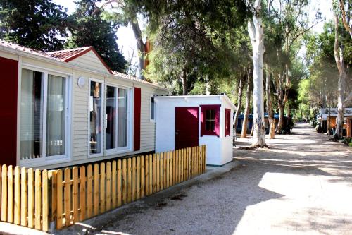 a red and white house with a fence next to it at Camping Cases in Les Cases d'Alcanar