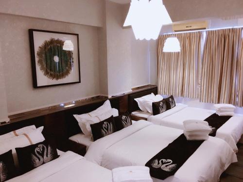 香港にあるSeasons Hotel - Causeway Bayのベッド3台とシャンデリアが備わるホテルルームです。