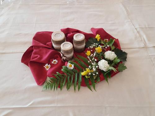 a bouquet of flowers and three bottles on a bed at Caminetto Mountain Resort in Lavarone