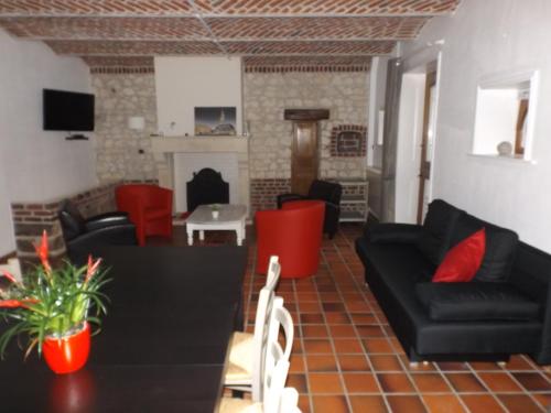 a living room with black furniture and red chairs at Le gite des Menhirs in Mont-Saint-Éloi