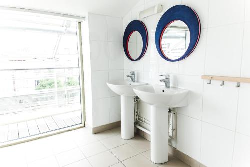 a bathroom with two sinks and a mirror on the wall at St Christopher's Inn Paris - Canal in Paris