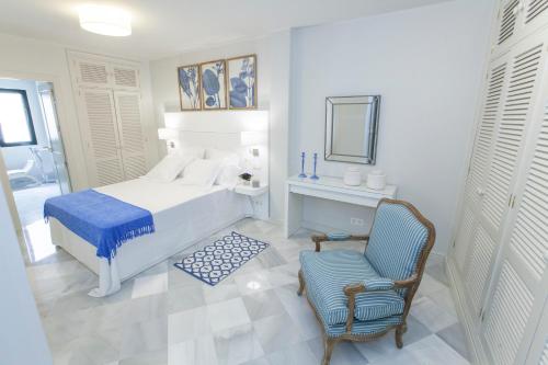 biała sypialnia z łóżkiem i krzesłem w obiekcie GR Suites Boutique Picasso w Maladze