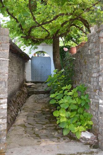 a stone walkway with a tree and a white door at Guesthouse Mele in Gjirokastër