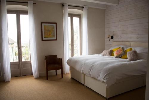 una camera da letto con un letto, una sedia e finestre di La-Villanelle - Magnifique vue sur le lac, 5 minutes à pied de la plage a Veyrier-du-Lac