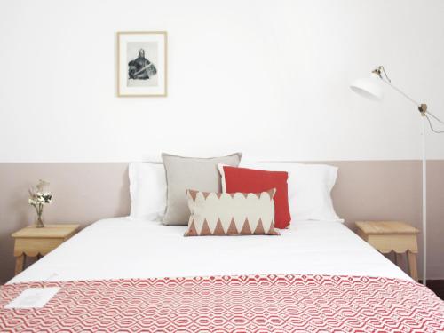 Foral Guest House - Óbidos في أوبيدوس: غرفة نوم بسرير ابيض ومخدات حمراء