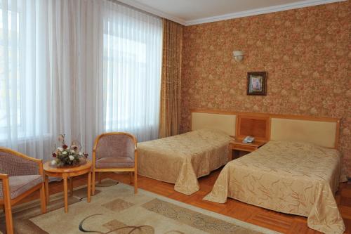 Cette chambre d'hôtel comprend deux lits, une table et des chaises. dans l'établissement Gostinichny Komplex Germes, à Karaganda