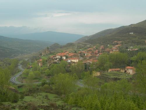 un pequeño pueblo en una colina con un camino sinuoso en La Colmena, en Navalsaz