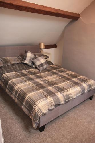 ein Schlafzimmer mit einem Bett mit einer karierten Decke in der Unterkunft Delfryn Cottage in Rhayader