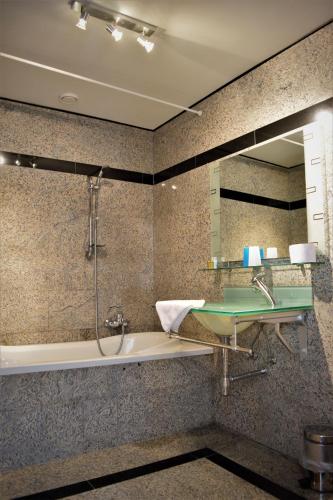 a bathroom with a tub and a sink and a mirror at Hotel Maurice in Nieuwvliet