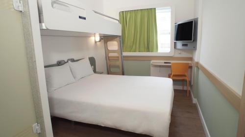 a small room with a white bed and a television at ibis budget Osasco in Osasco