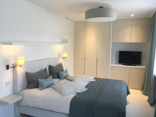 a bedroom with a bed with pillows and a tv at Villa Emilia in De Haan