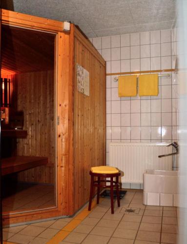 a bathroom with a wooden door and a stool in it at Ferienwohnungen Egon Schulz in Zempin