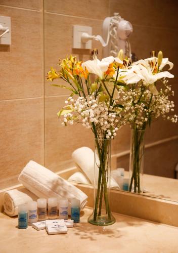 a vase of flowers on a table in front of a mirror at Hotel Howard Johnson Trenque Lauquen in Trenque Lauquen