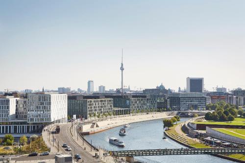 a river with boats in a city with buildings at Steigenberger Hotel Am Kanzleramt in Berlin