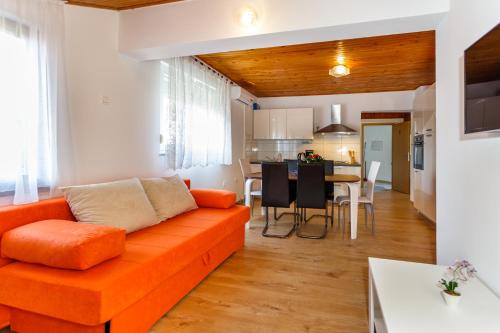 a living room with an orange couch and a kitchen at Apartmani M in Baška