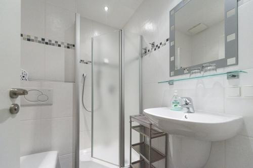 uma casa de banho branca com um chuveiro e um lavatório. em Weingut Karl Braun em Nordheim