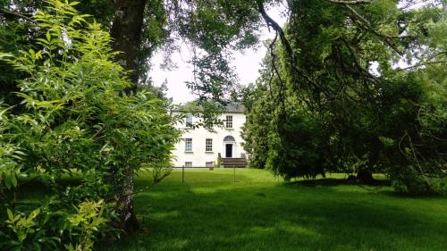 a white house in the middle of a yard with trees at Augherea House in Longford