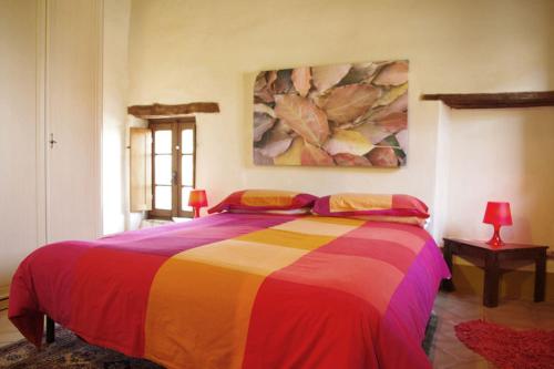 Farmhouse Tuscany في Montecastelli Pisano: غرفة نوم مع سرير ملون مع لوحة على الحائط