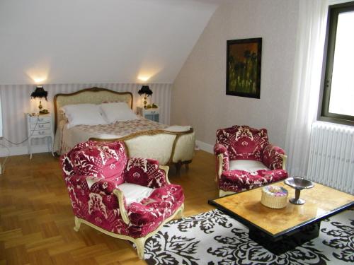 een slaapkamer met een bed en 2 stoelen en een tafel bij Chambre d'hotes La Jaunais in Virey