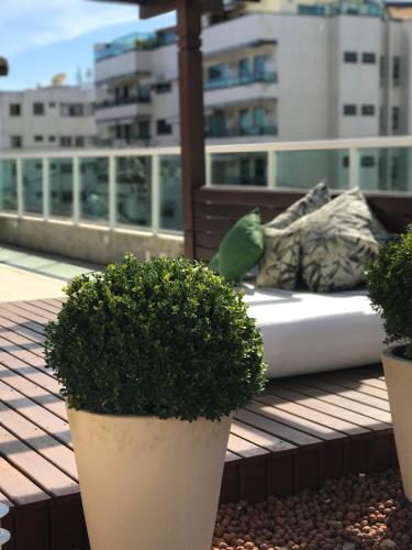 a bed on a balcony with two potted plants at Pousada Mariá in Cabo Frio