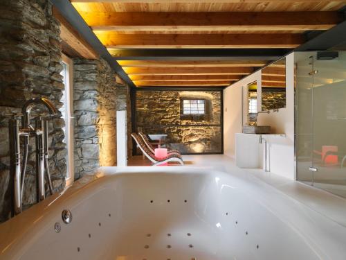 a large bath tub in a room with a stone wall at Le Coffret in Saint Marcel