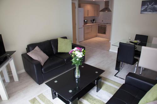 a living room with a couch and a table with flowers at City Centre Luxury Holiday Apartment in Liverpool