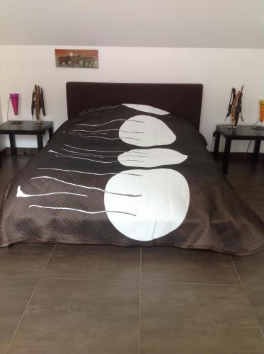 a bed with a black and white comforter on it at Le Sérènity in Le Landin
