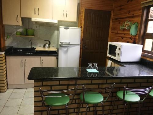a kitchen with a counter with chairs and a refrigerator at Pousada Esperança in Osório