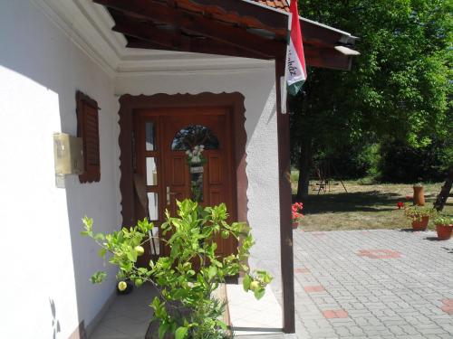 a white house with a wooden door and a plant at Jakuzzis,Szaunás,Kerkavendégház-Őrség-Csesztreg-Kerkaujfalu in Csesztreg