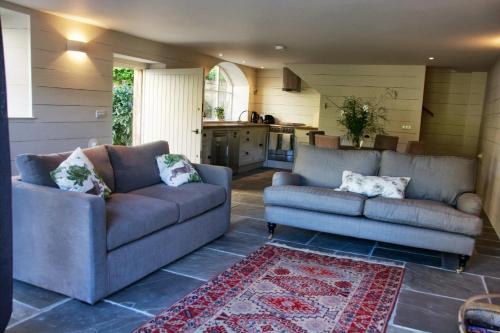 ein Wohnzimmer mit 2 Sofas und einer Küche in der Unterkunft Ivythorpe Coach House in Bath