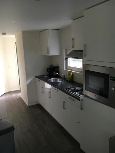 a kitchen with white cabinets and a sink and a microwave at Vakantiecentrum De Ullingse Bergen in Sint Anthonis